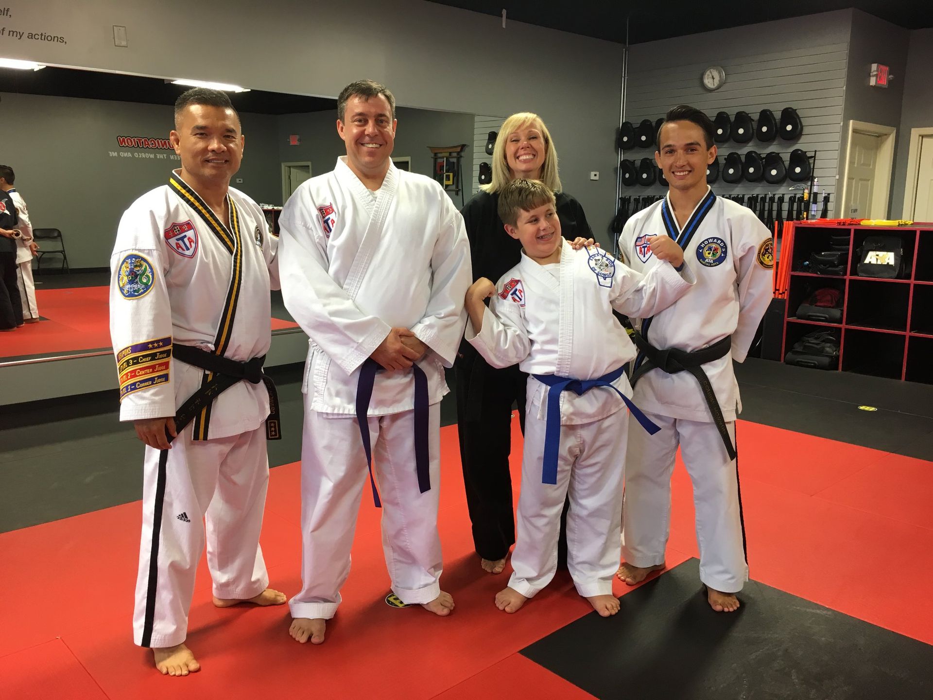 A group of people in karate uniforms are posing for a picture in a gym.