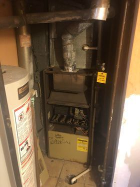 Furnace and water heater in an alcove. Beige furnace with venting and pipes. Water heater on the left.