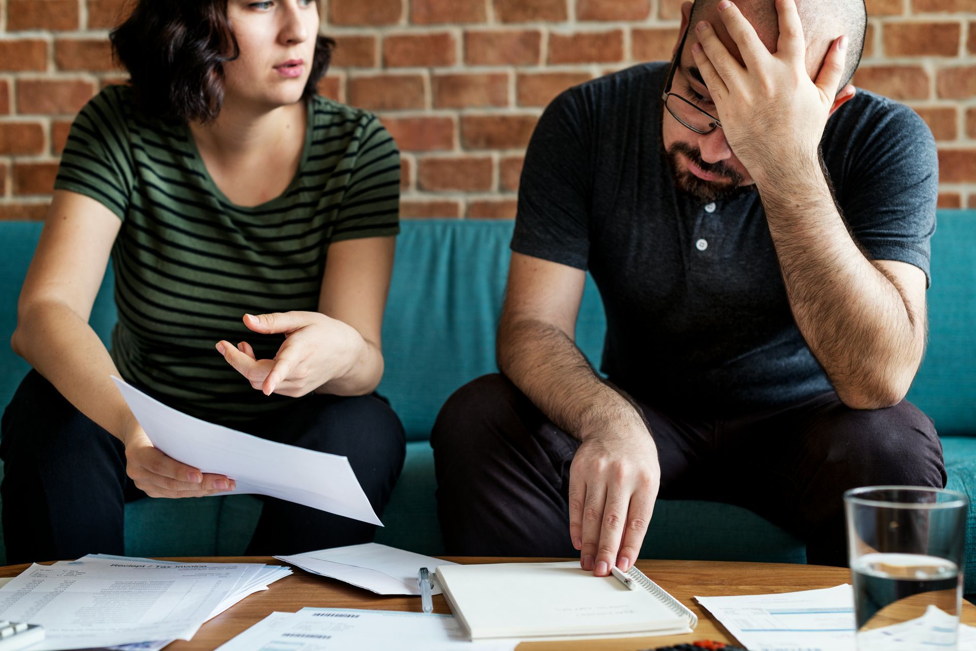 A man and a woman are sitting on a couch looking at papers.