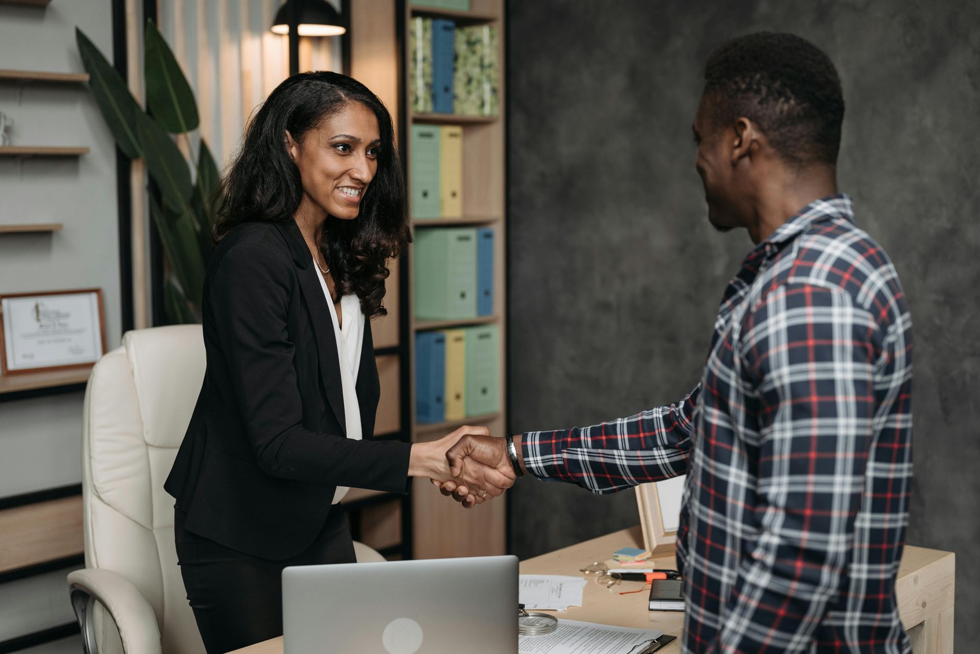 A woman is shaking hands with a man in an office.