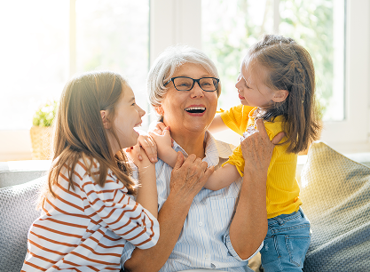 An elderly woman is sitting on a couch with two little girls.