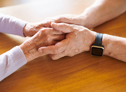 A man and a woman are holding hands on a wooden table.