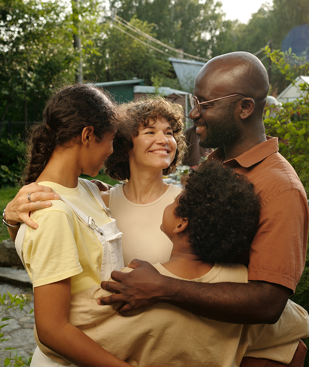 A man is holding a child in his arms while standing next to a woman and two girls.