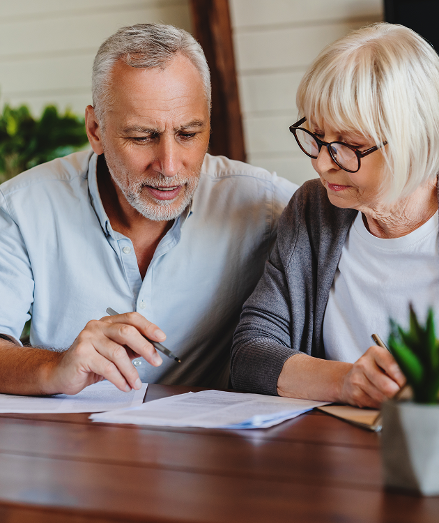 A man and a woman are sitting at a table looking at a piece of paper.