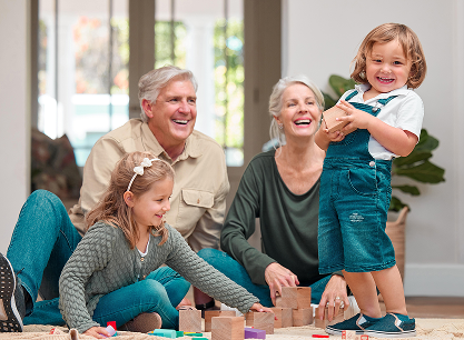 A family is sitting on the floor playing with wooden blocks.