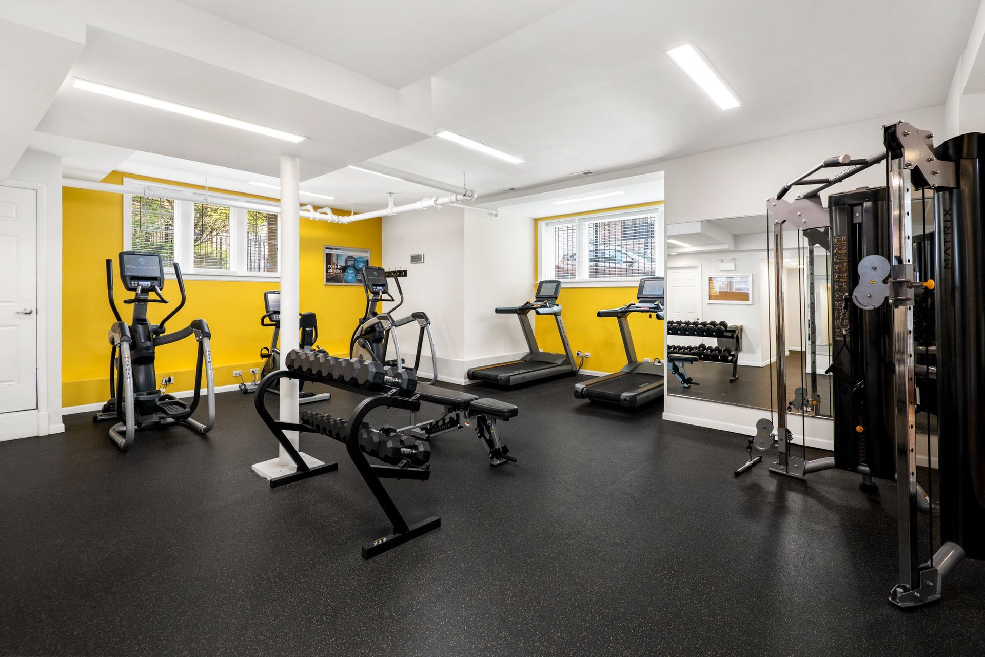 A gym with a lot of equipment and a yellow wall.