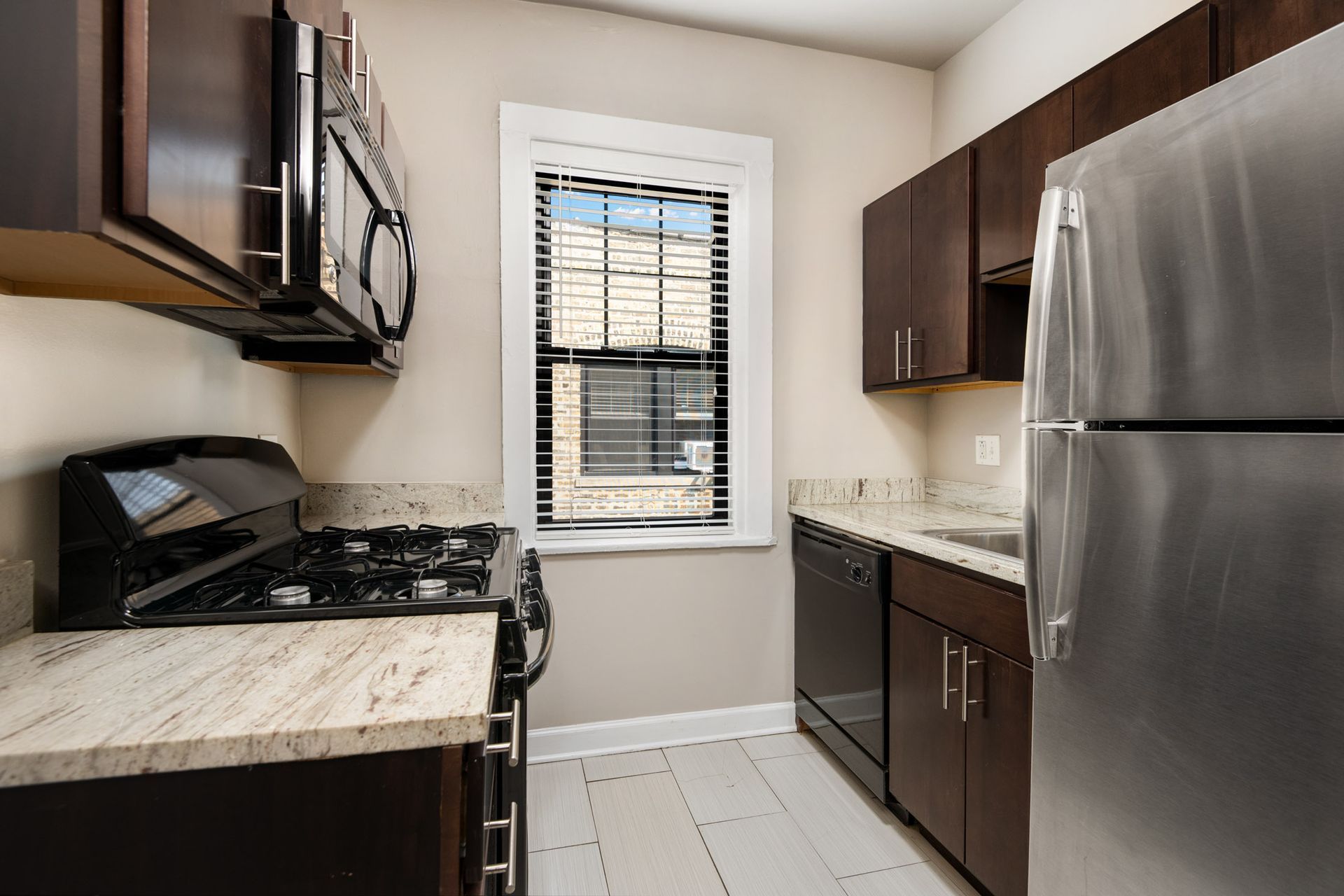 A kitchen with stainless steel appliances and wooden cabinets at Irving Courts by Reside.