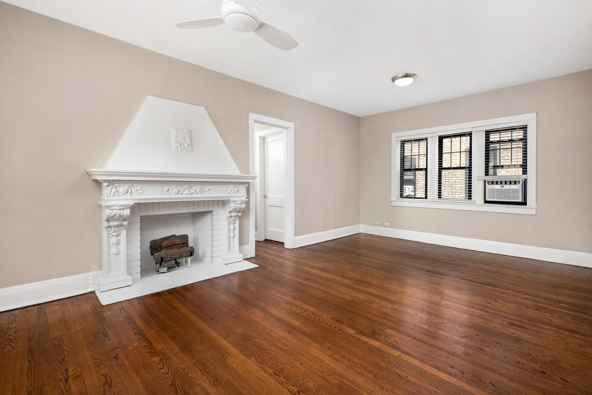 An empty living room with hardwood floors and a fireplace at Irving Courts by Reside.