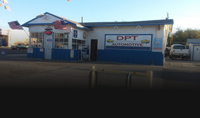DPT Automotive building, blue and white, American flags, sign, cars parked outside.