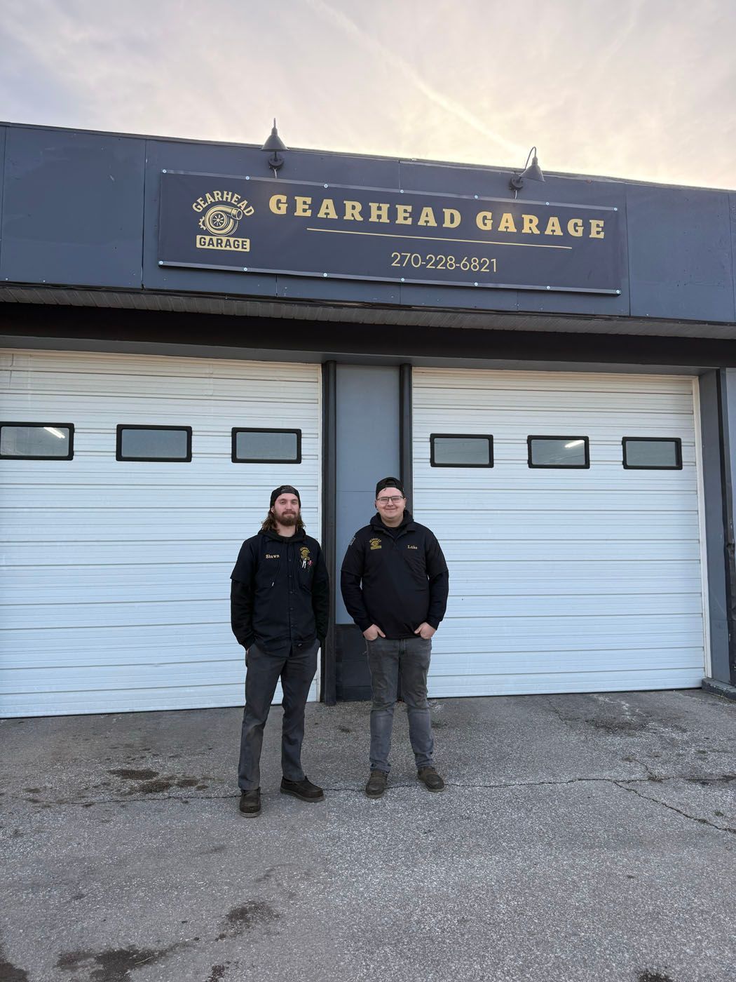 Two people standing outside Gearhead Garage in front of blue garage doors