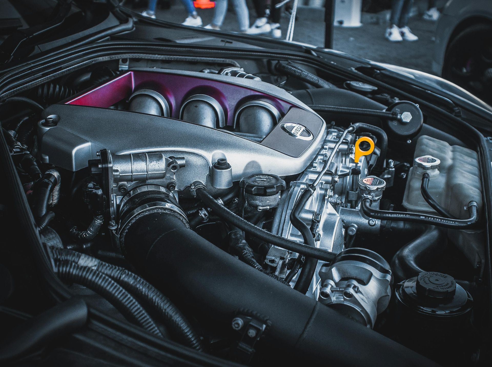 Open car engine bay with polished purple intake manifold and yellow dipstick handle