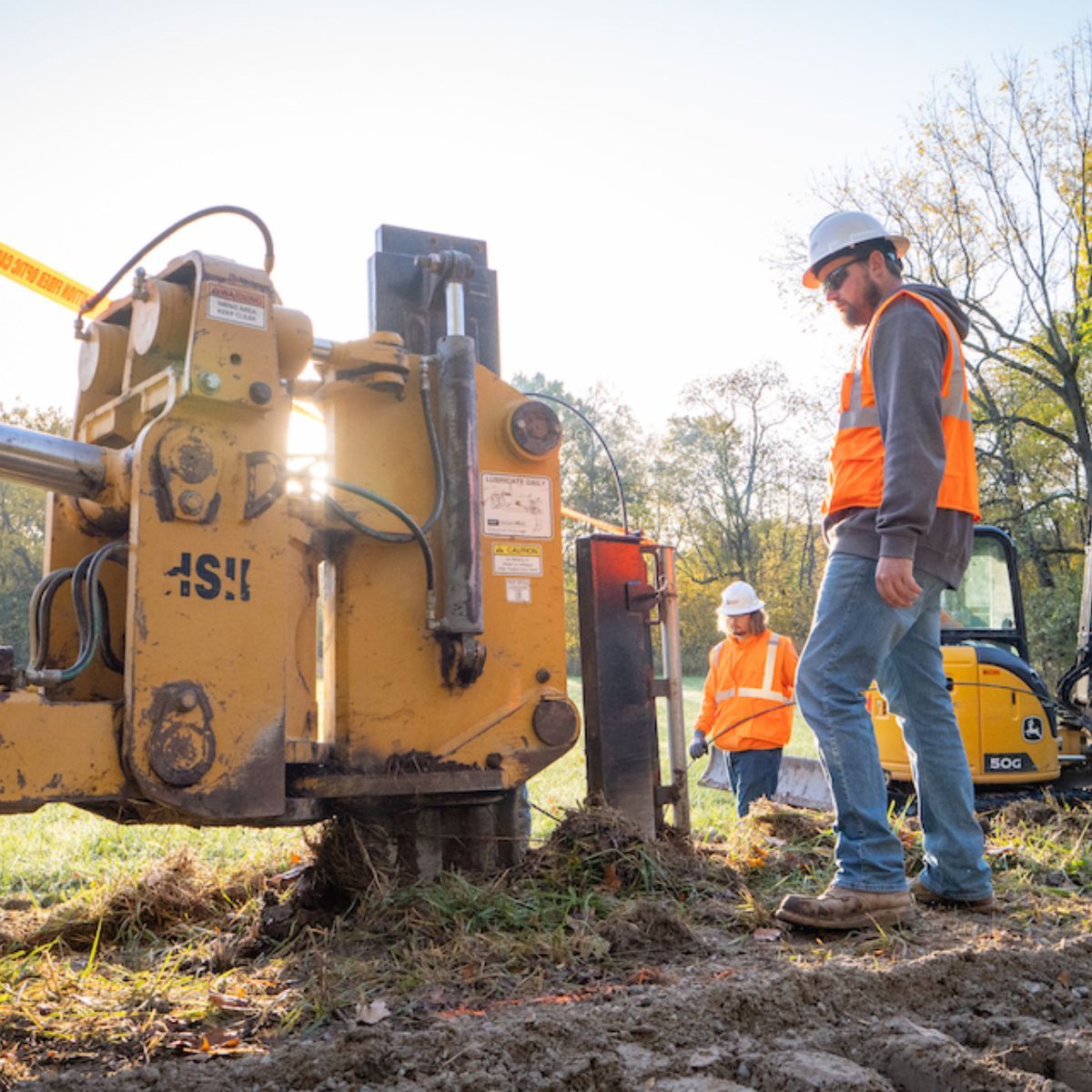 A man in a hard hat is standing next to a machine that says ' ash ' on it.