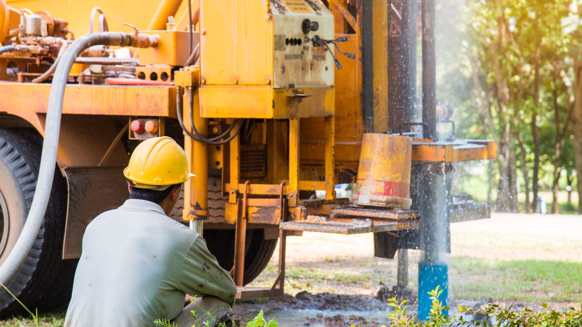 A man wearing a hard hat is sitting in front of a truck.