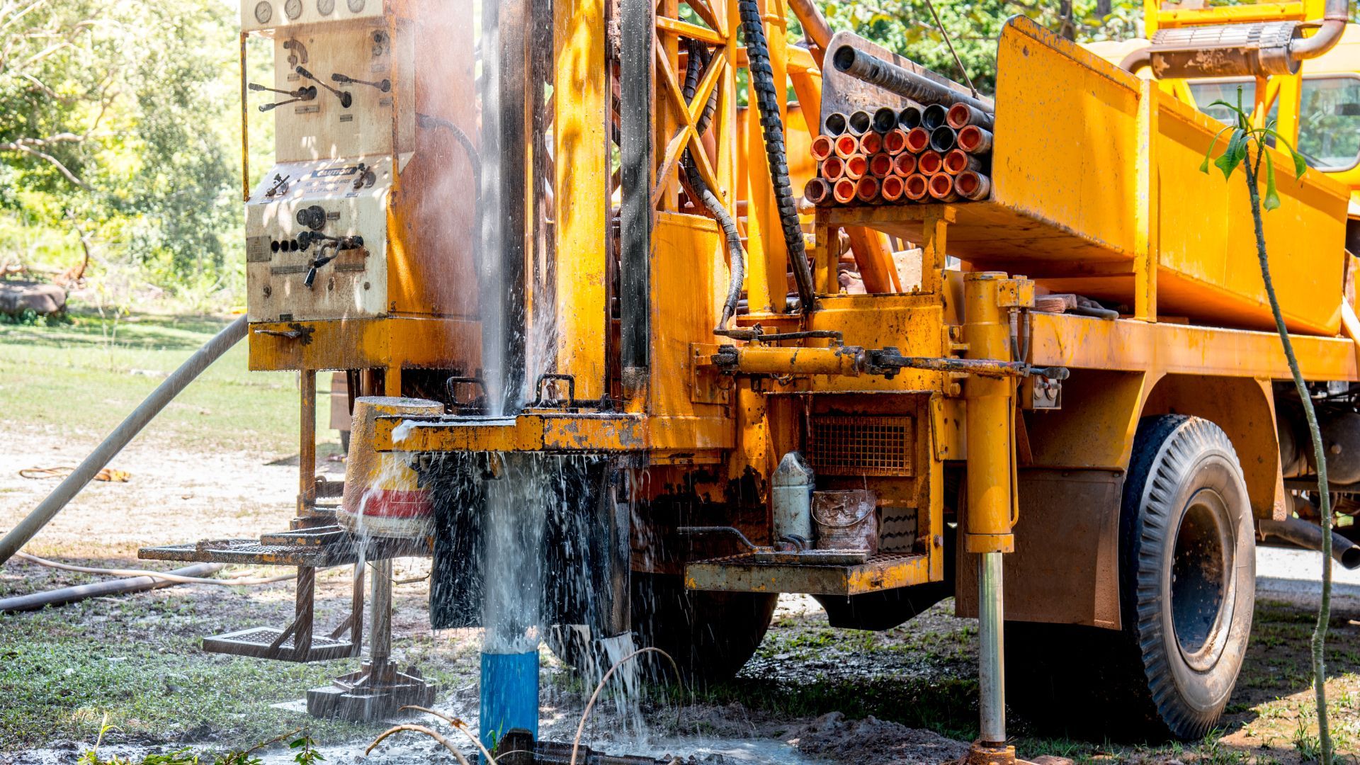 A yellow truck is drilling a hole in the ground.