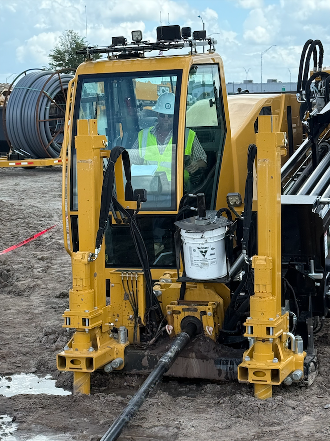 A man wearing a hard hat is sitting in front of a truck.
