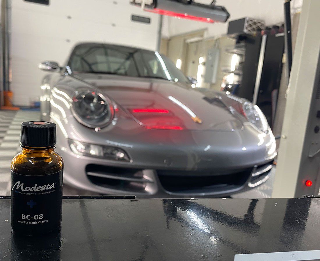 A bottle of moderna sits next to a car