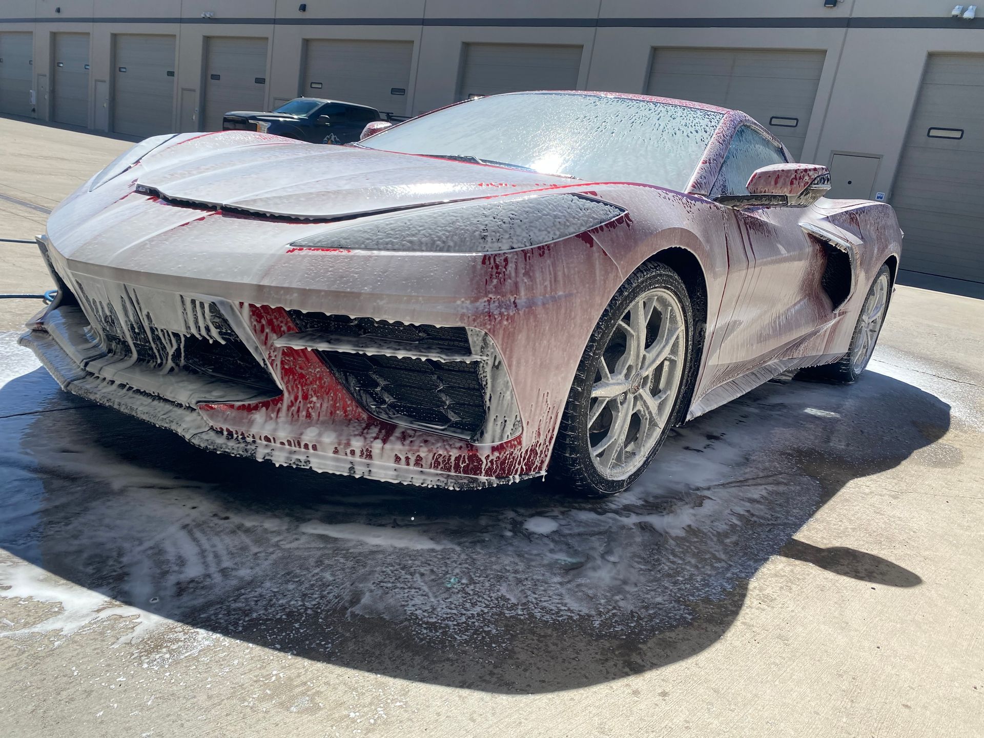 A sports car is covered in foam and sitting on the ground.