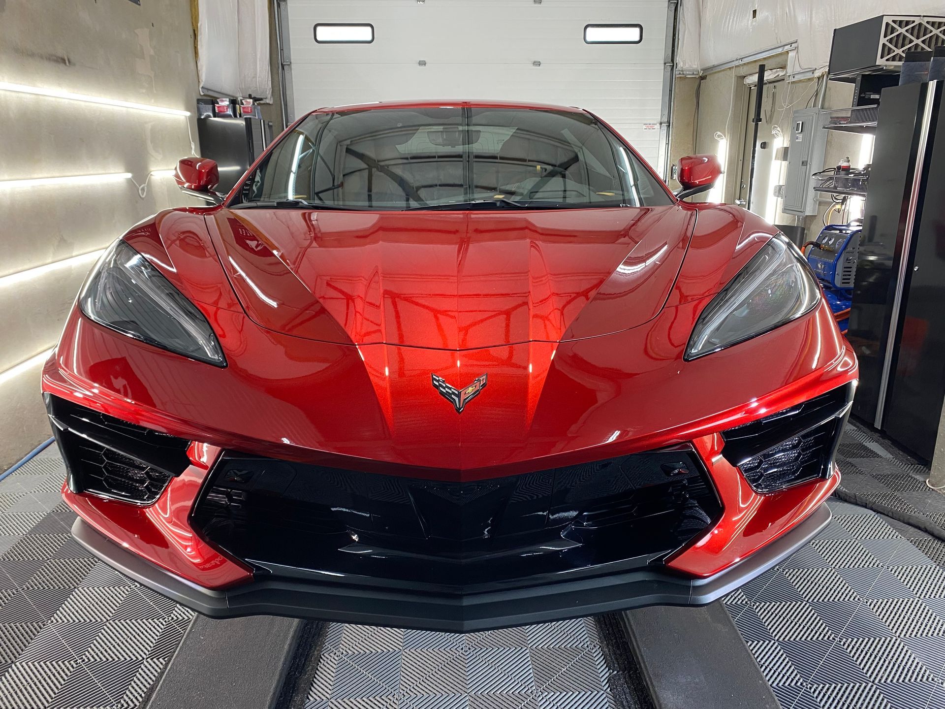 A red sports car is parked in front of a garage door.