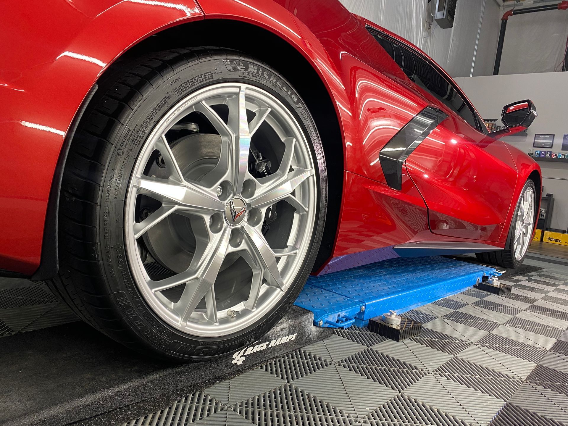 A red sports car is sitting on top of a blue ramp in a garage.