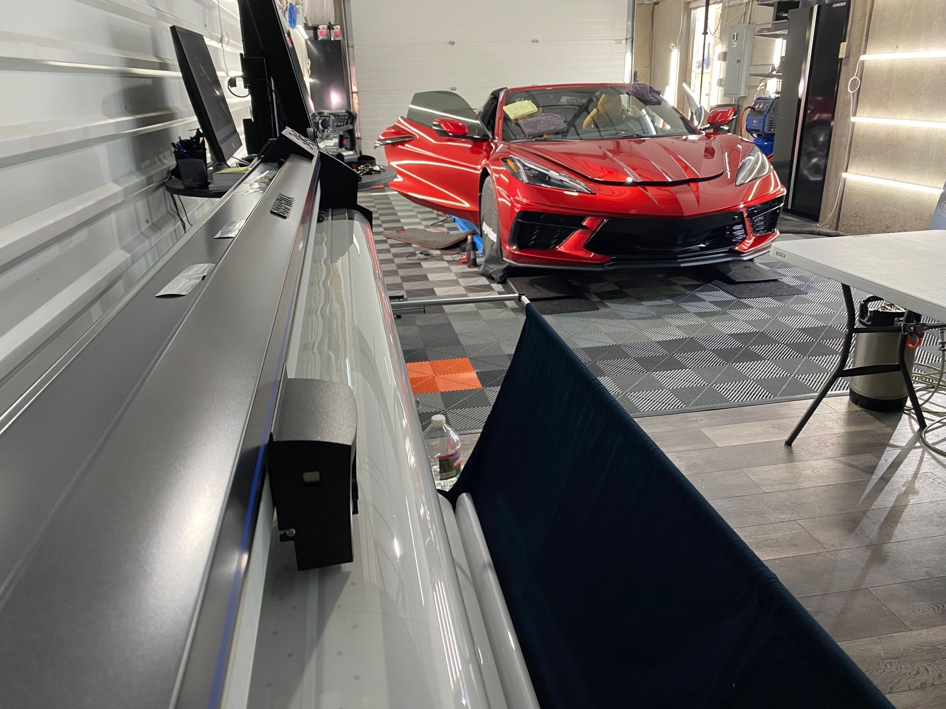 A red sports car is parked in a garage with its doors open.