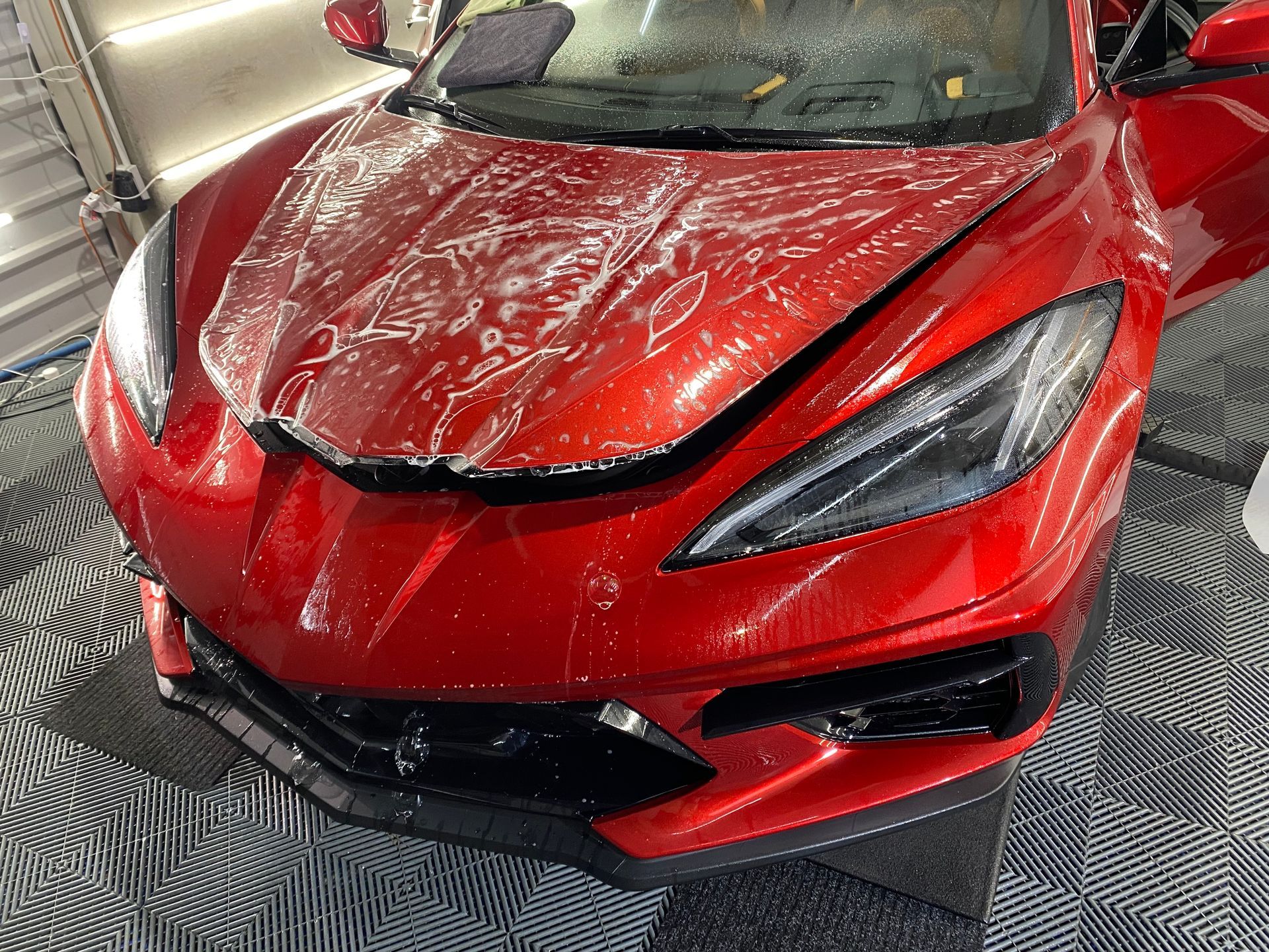 A red sports car is sitting on a tiled floor in a garage.