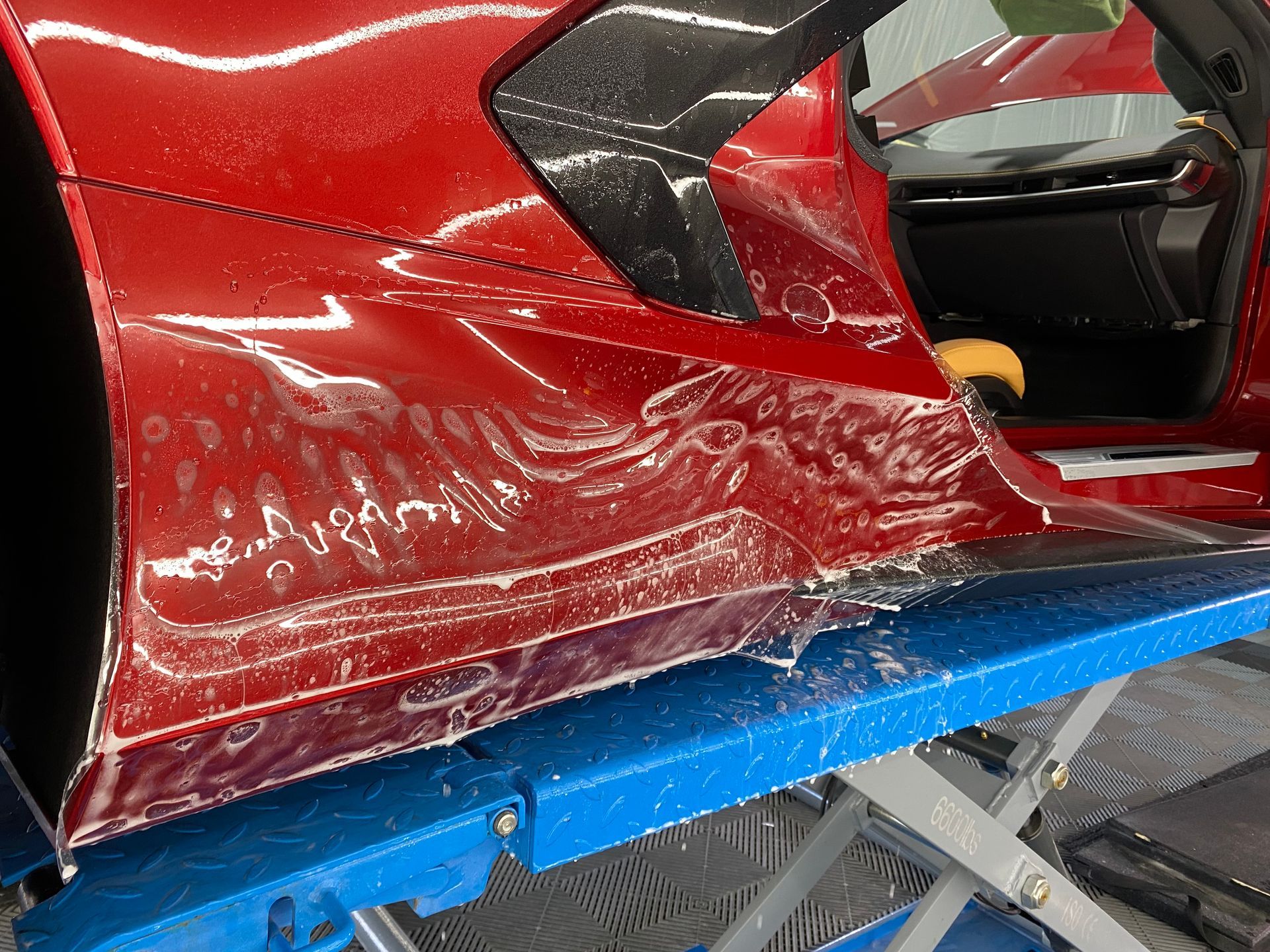 A red car is sitting on top of a blue lift.