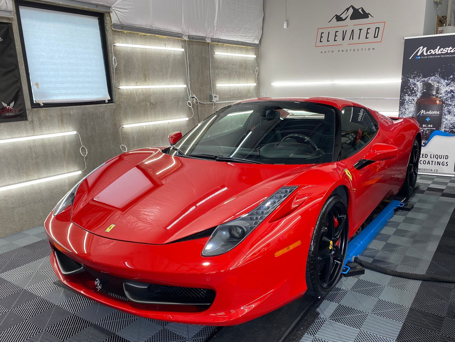 A red ferrari 458 italia is parked in a garage.