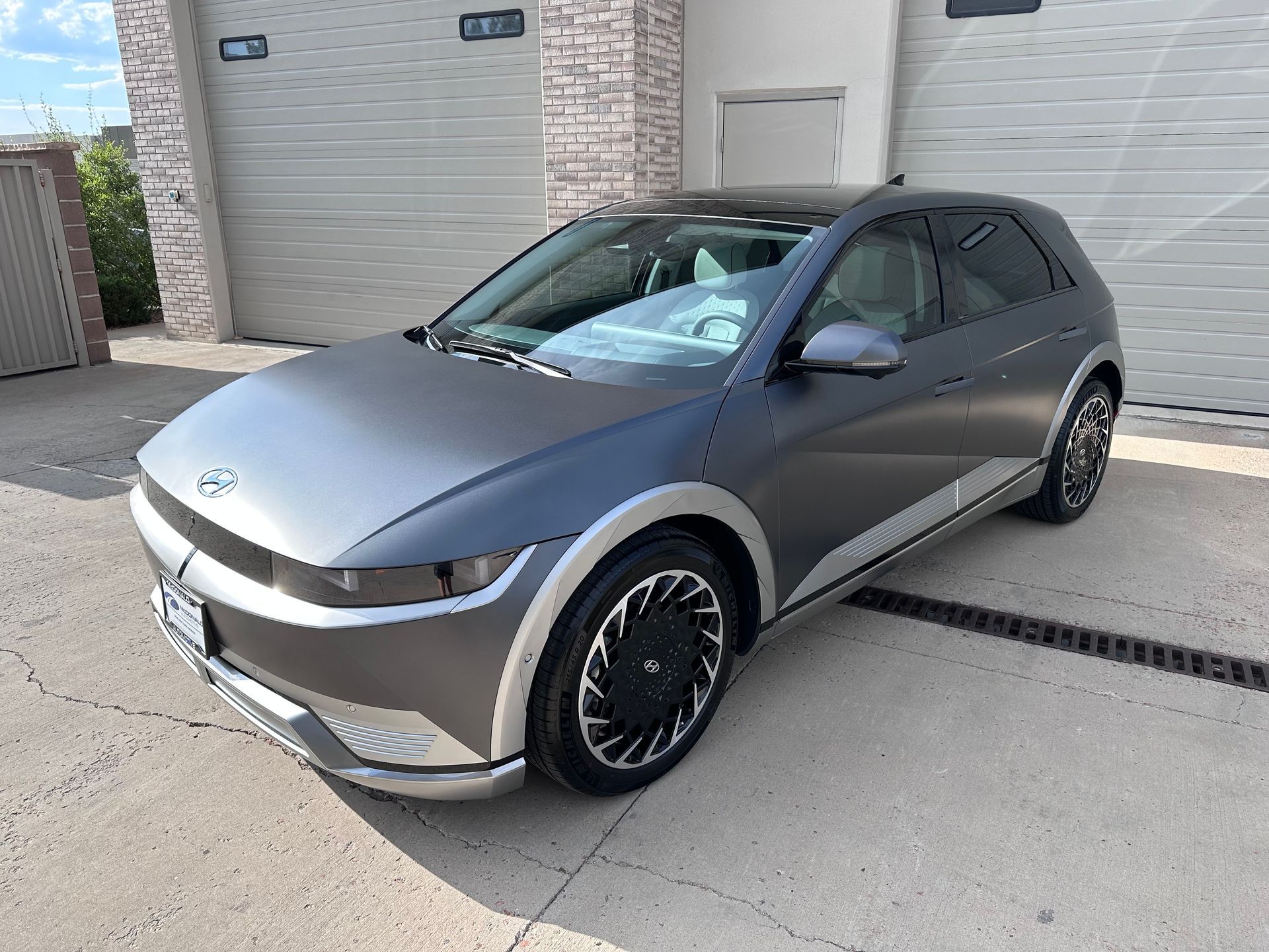 A gray car is parked in front of a garage door.