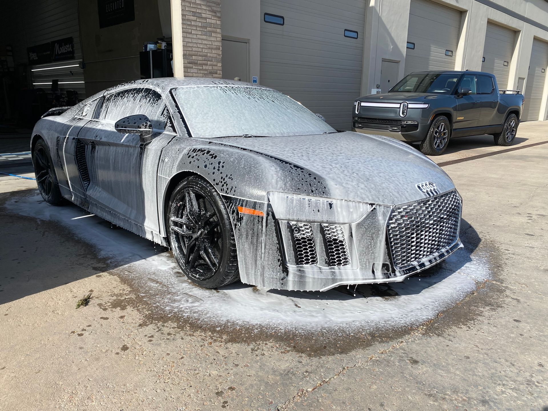 A car is covered in foam next to a truck.