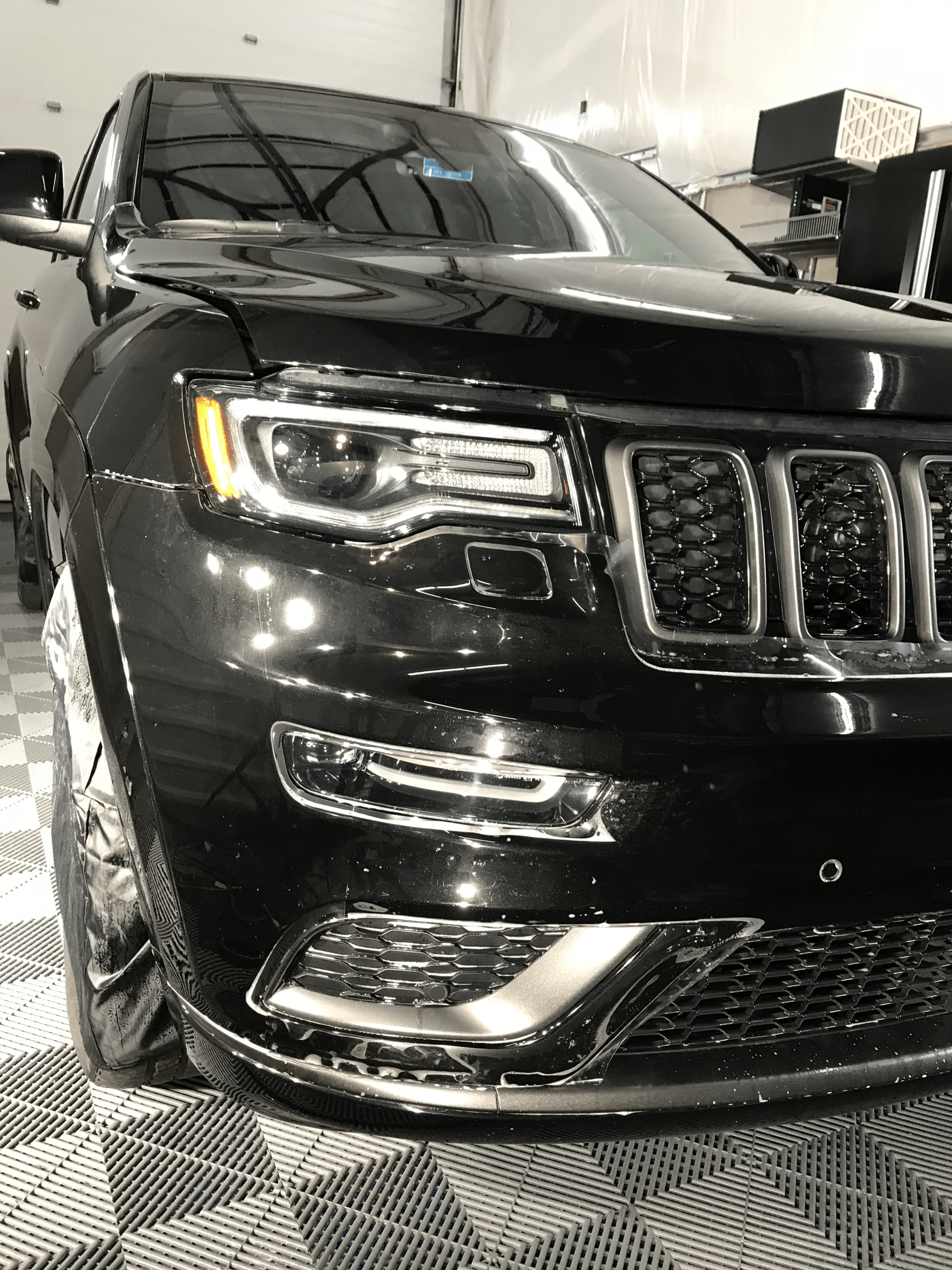 A black jeep grand cherokee is parked in a garage.