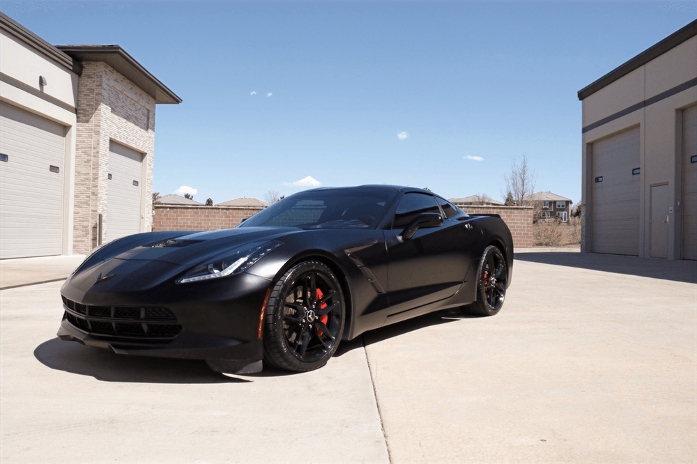 A black sports car is parked in front of a garage.