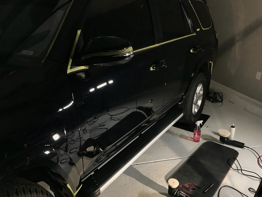 A black suv is sitting in a garage being polished.