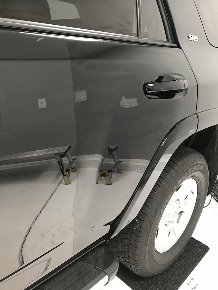 A close up of a car door with a white tire.