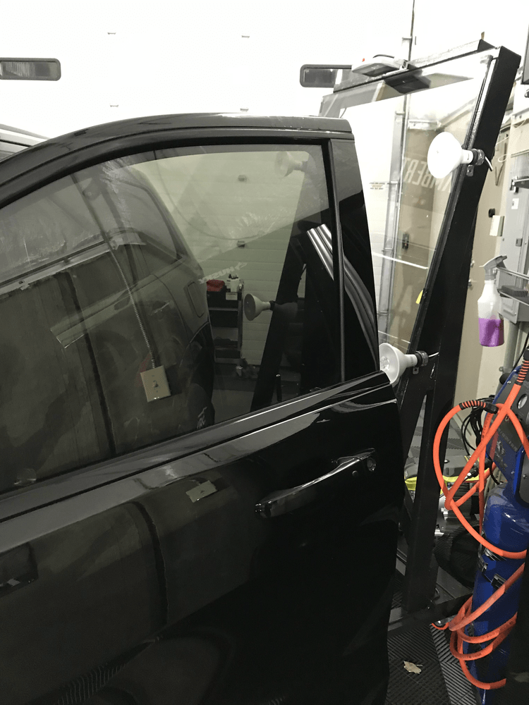 A black car is parked in a garage with the door open.