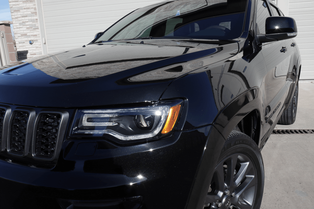 A black jeep grand cherokee is parked in front of a garage door.