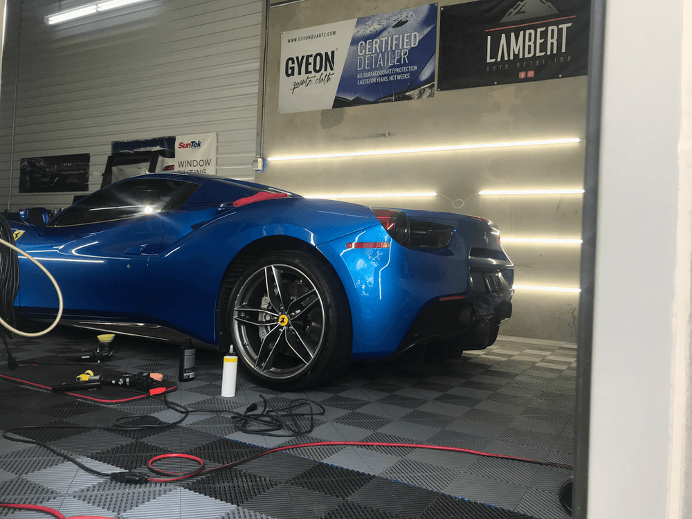 A blue sports car is being worked on in a garage.