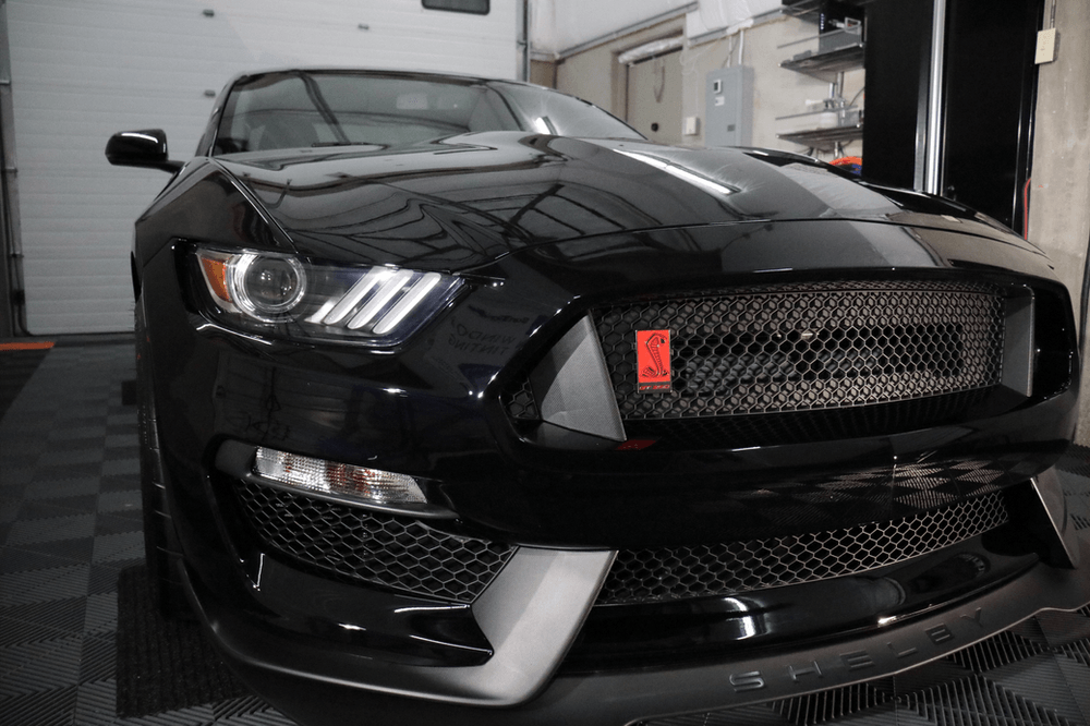 A black ford mustang is parked in a garage.