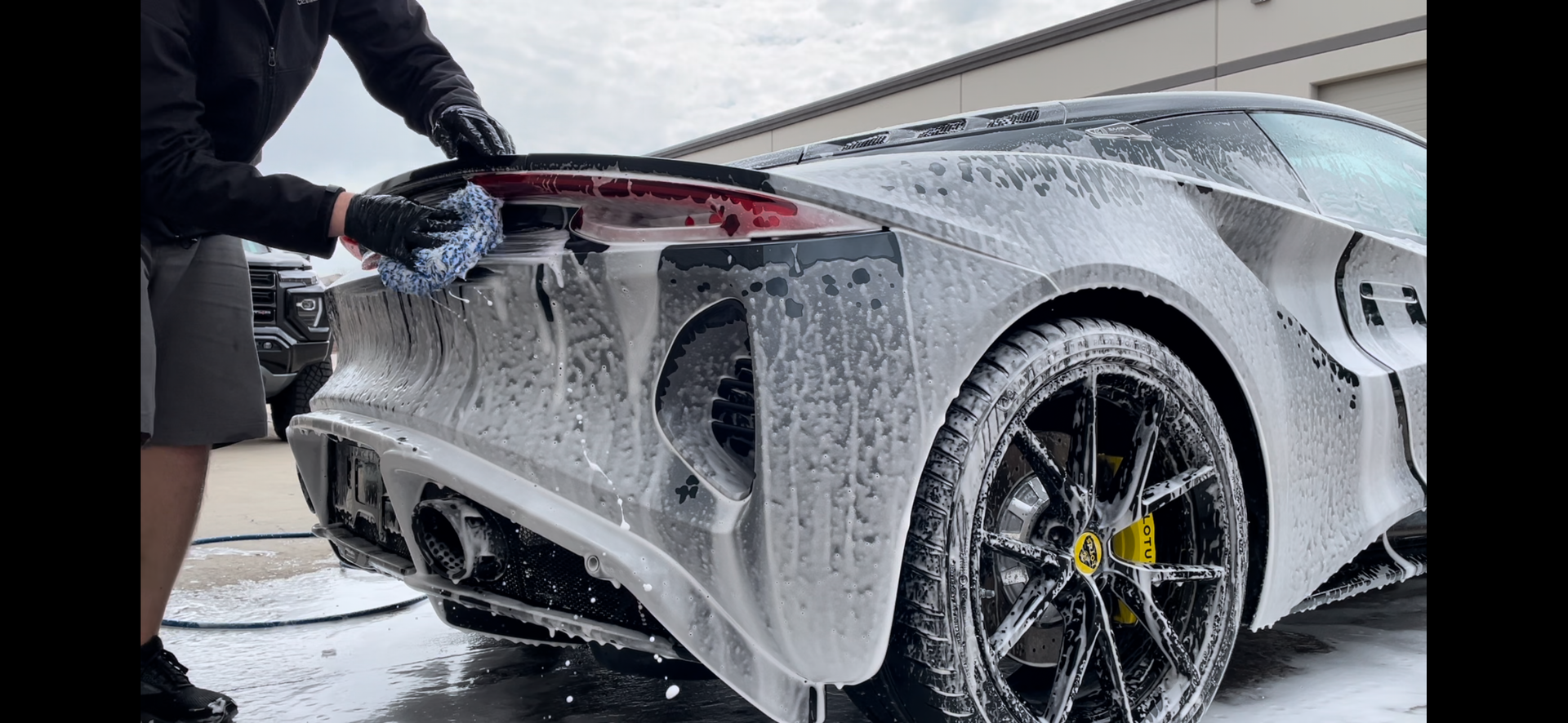 A man is washing a sports car with foam.