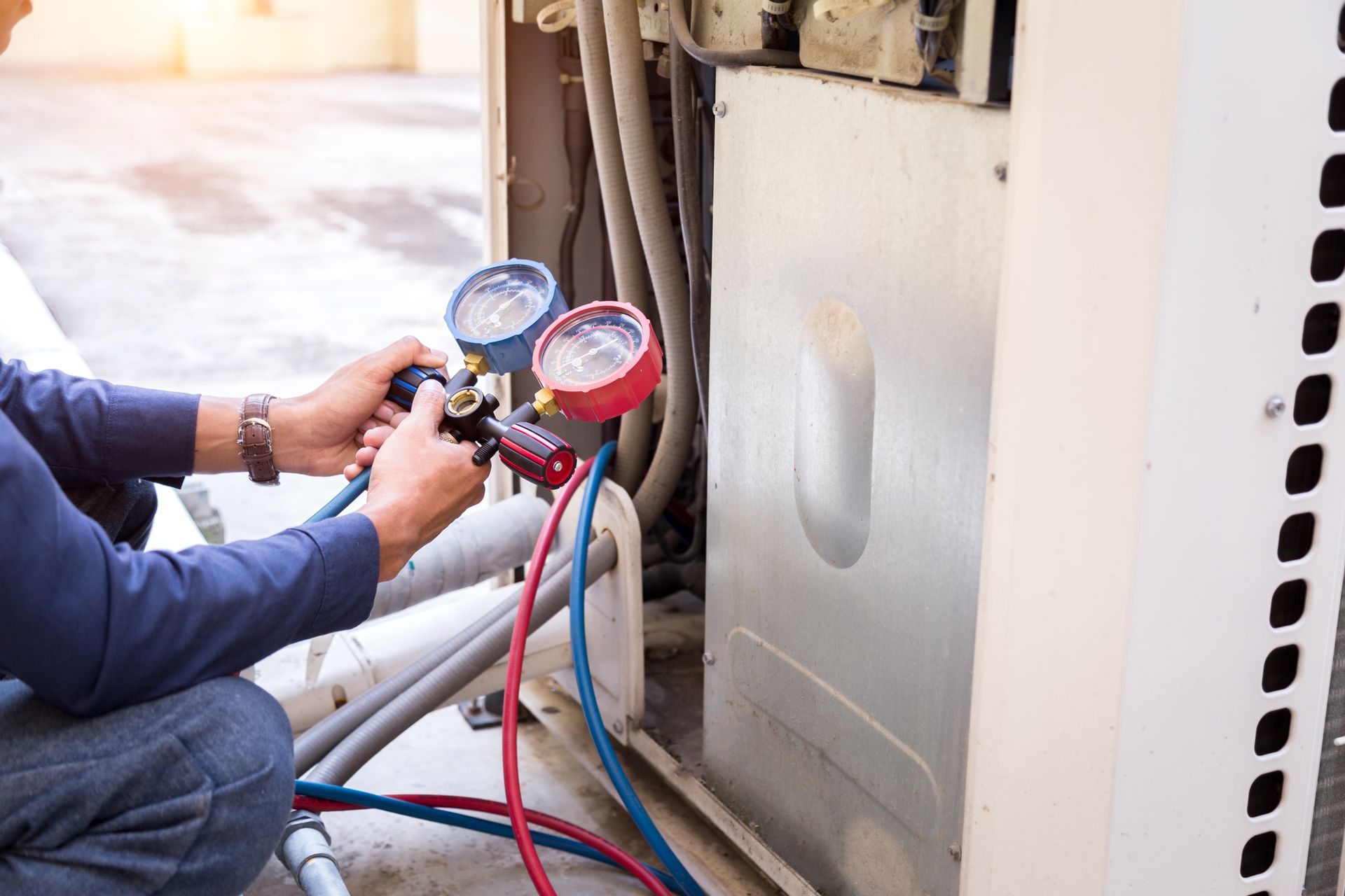 A man is kneeling down and working on an air conditioner.