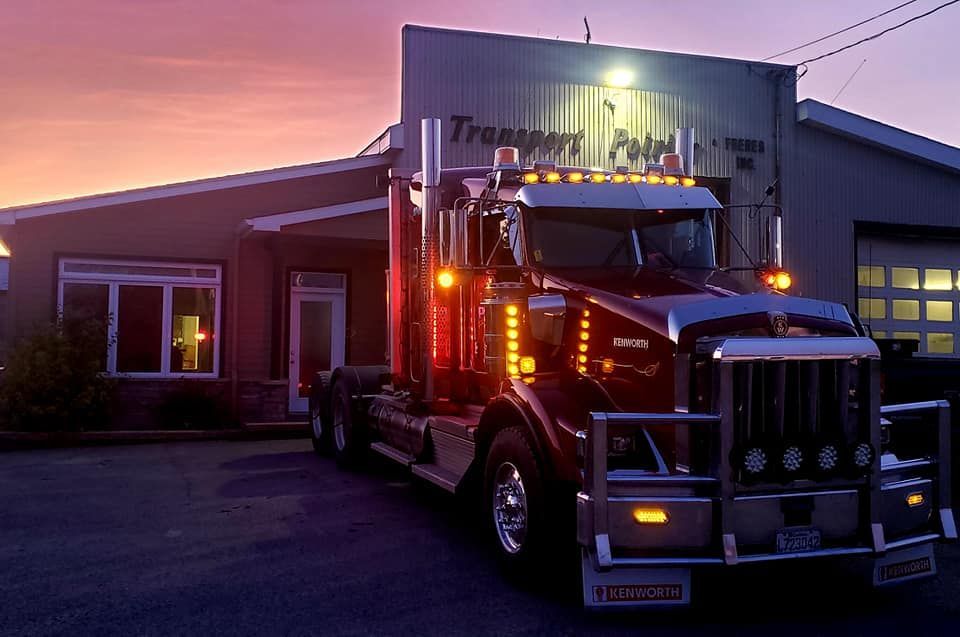 Un semi-remorque est garé devant un bâtiment avec le mot transport dessus