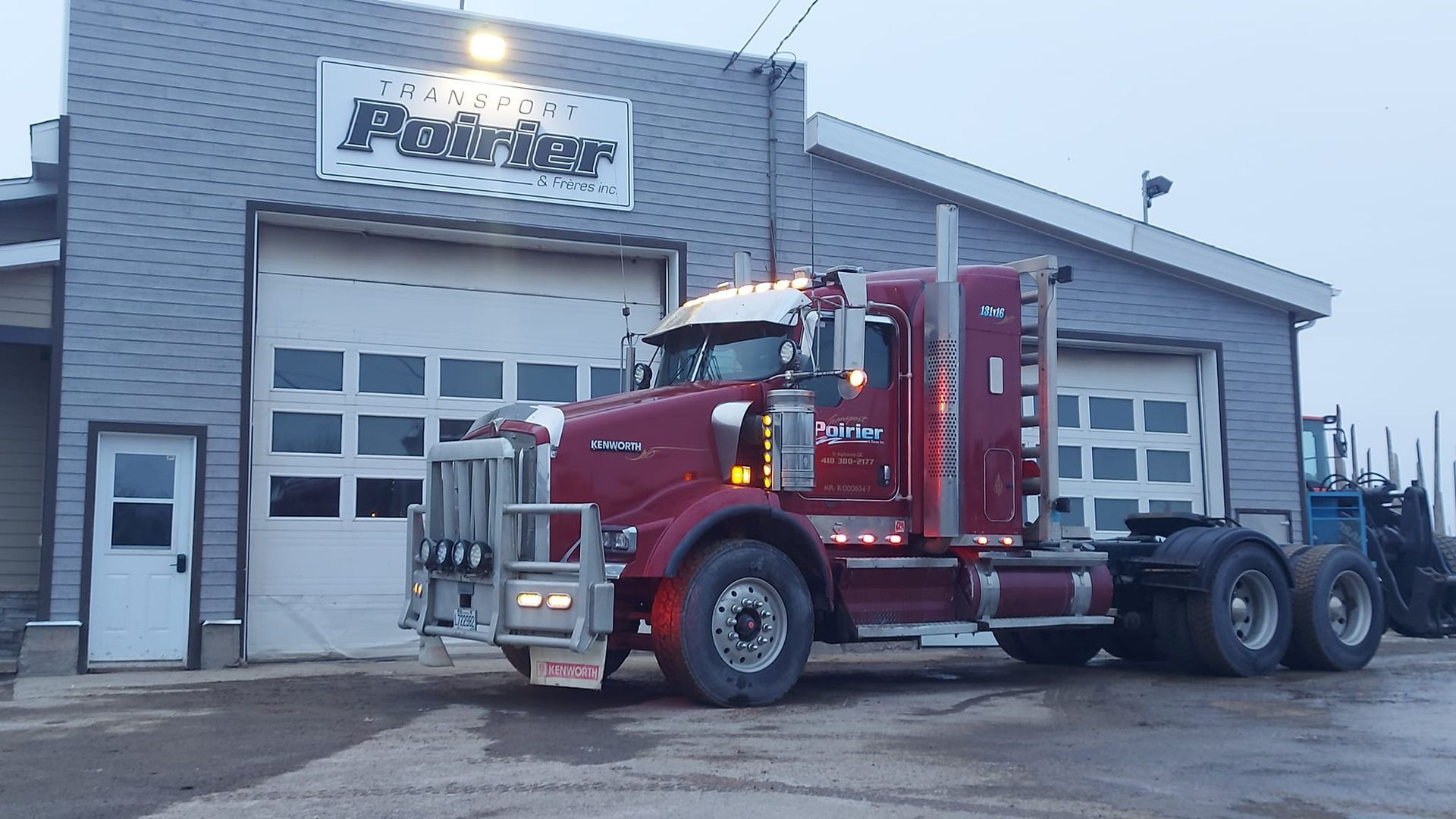 Un semi-remorque rouge est garé devant un bâtiment