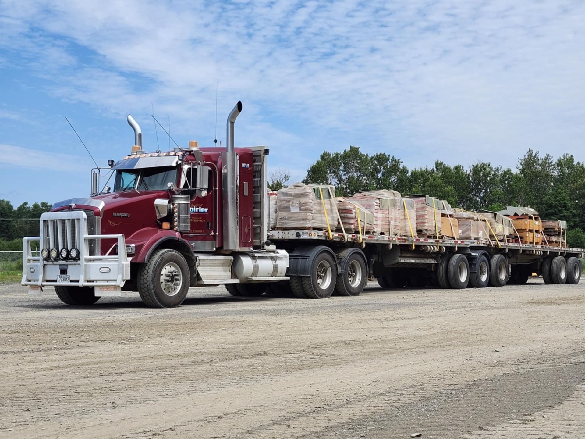 Un semi-remorque rouge avec une remorque à plateau pleine de briques