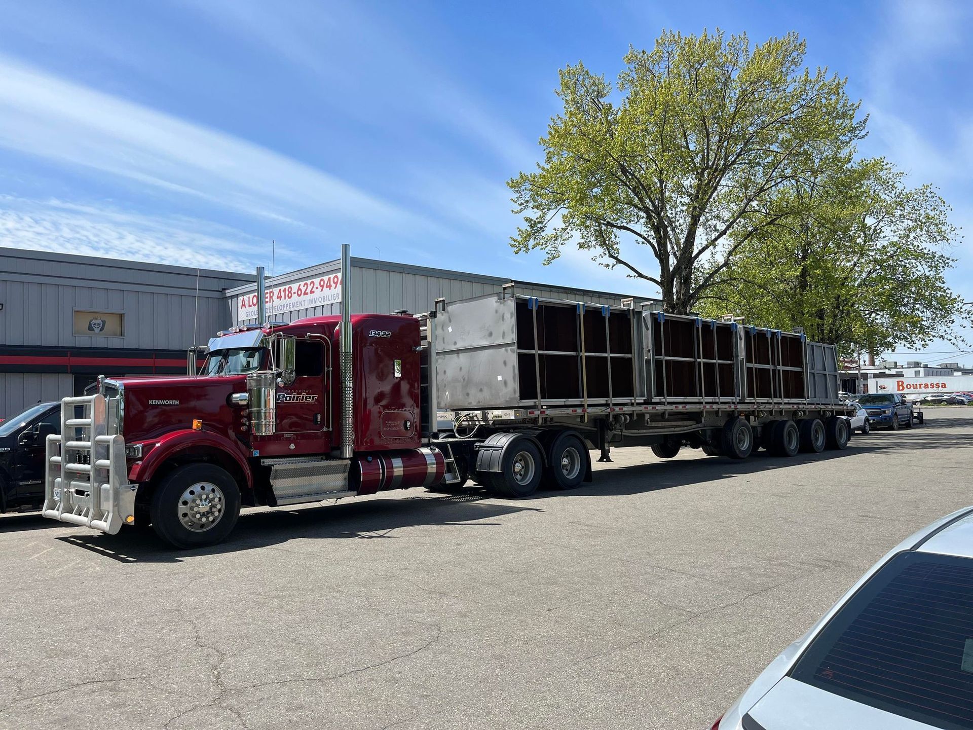 Un semi-remorque rouge est garé sur un parking à côté d'un bâtiment.