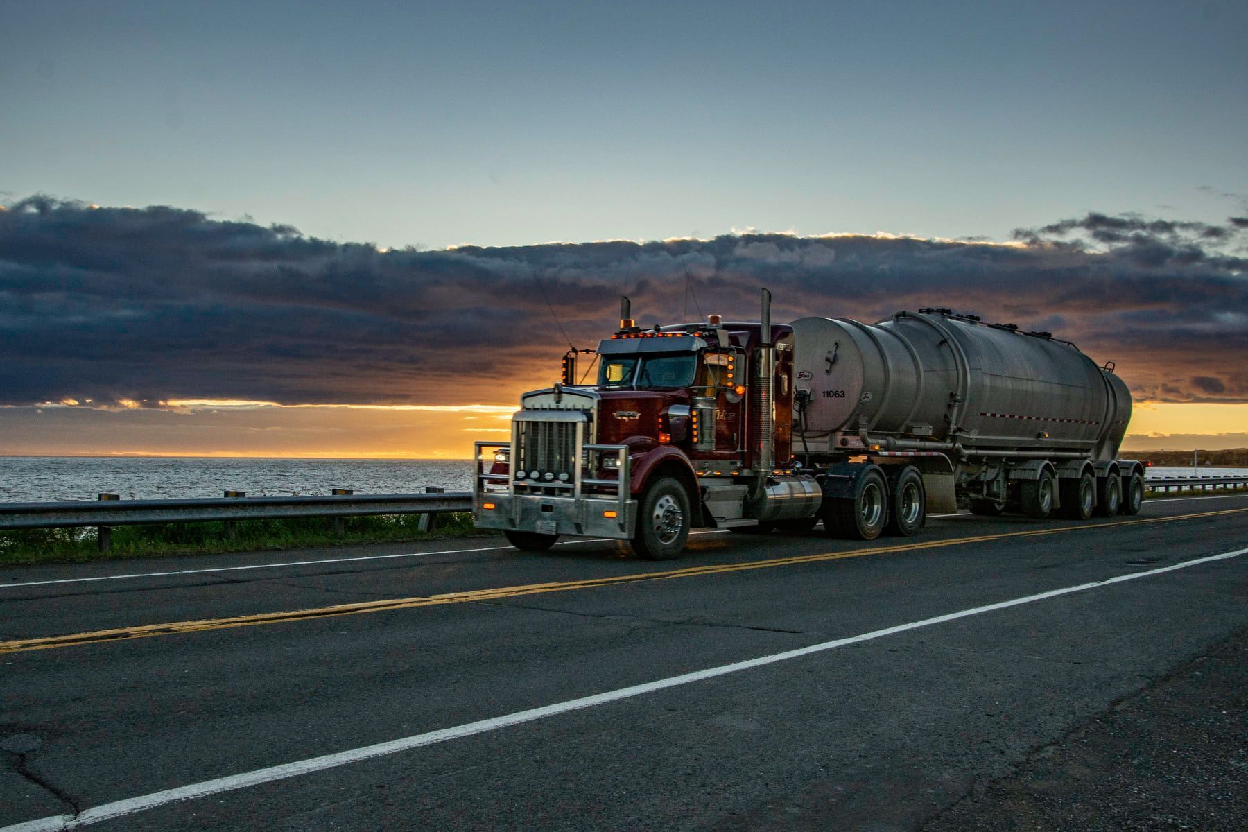 Un semi-camion roule sur une autoroute au coucher du soleil.