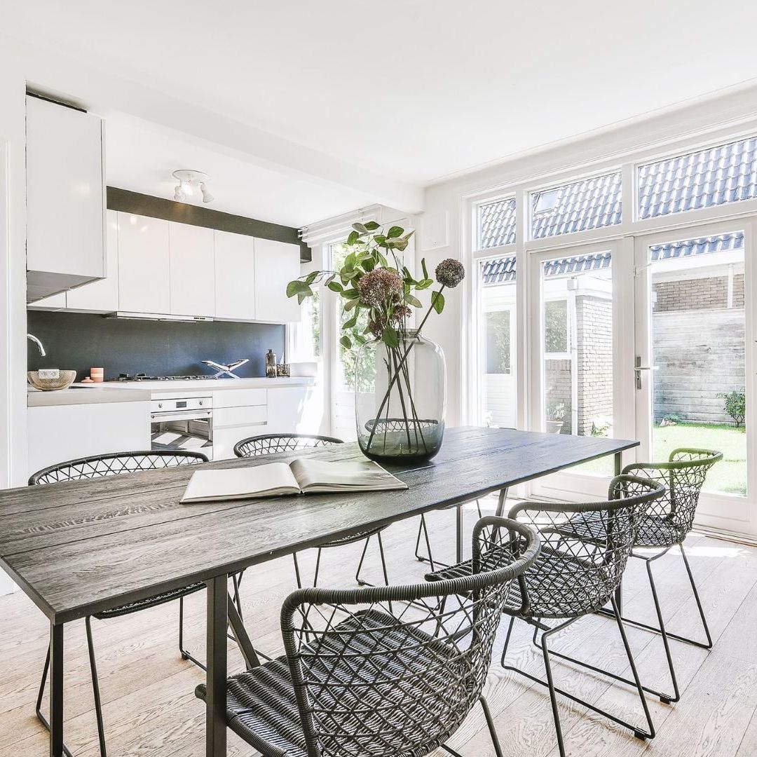 A dining room table with chairs and a vase of flowers on it.