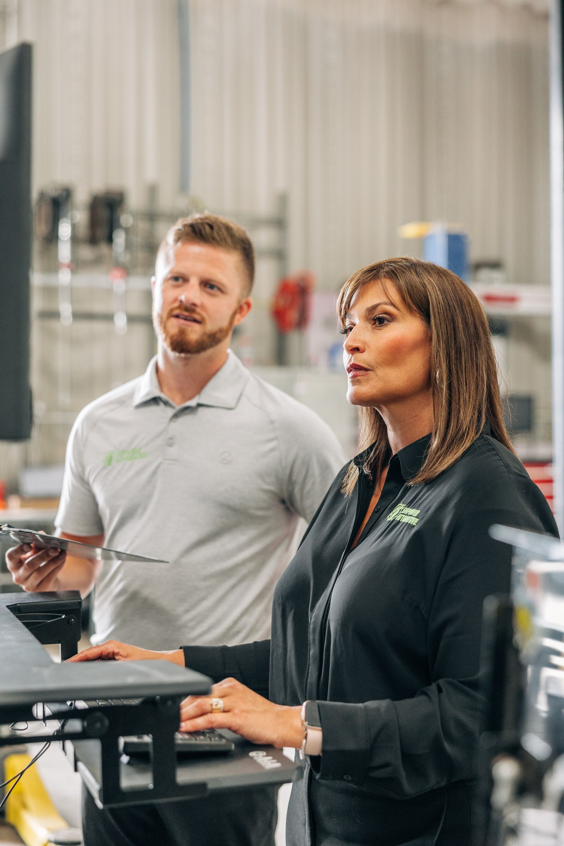 Woman and man looking at a computer screen in a warehouse. The woman is typing. | Empower Automotive