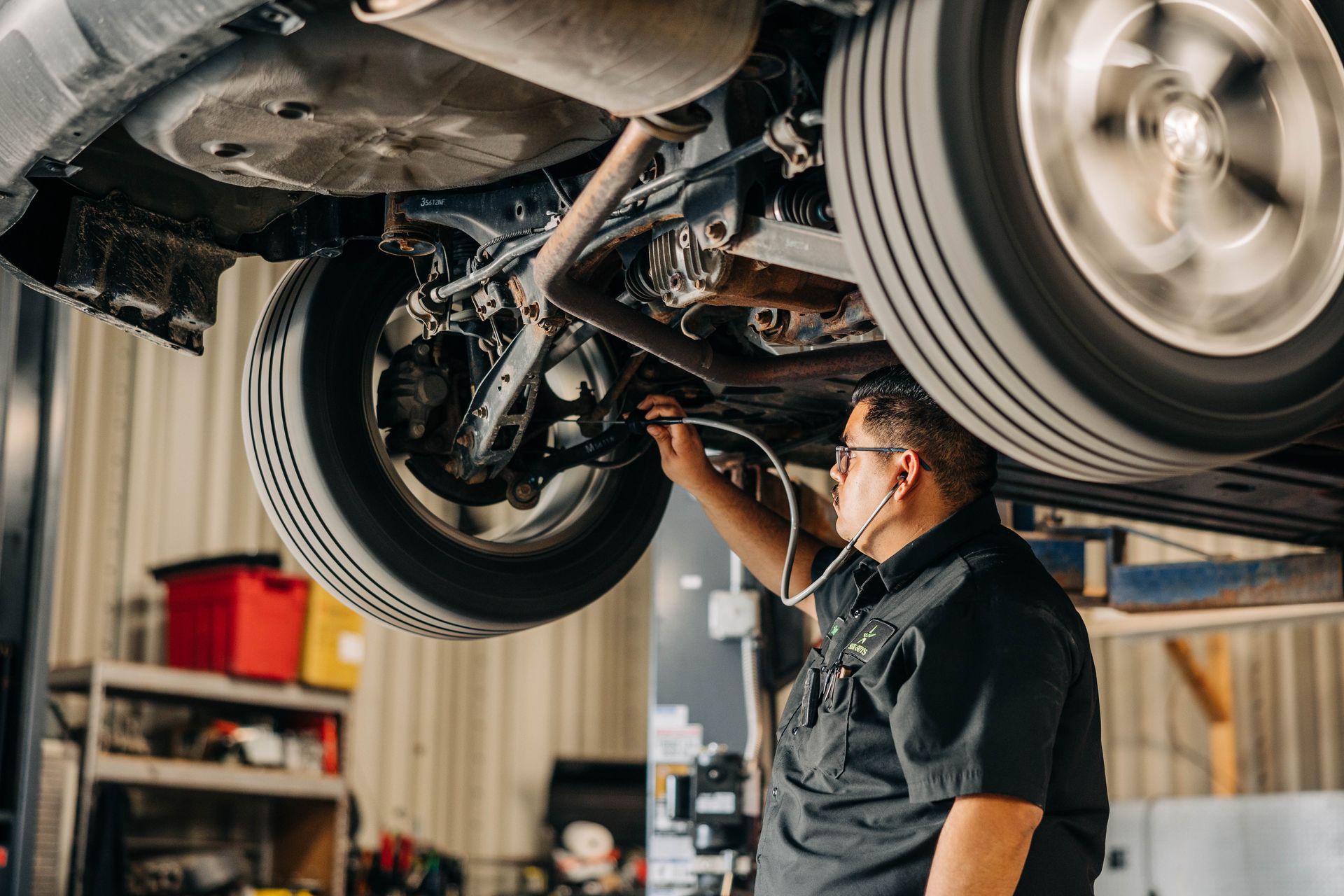 Mechanic inspecting a car lifted on a hoist in a workshop. | Empower Automotive