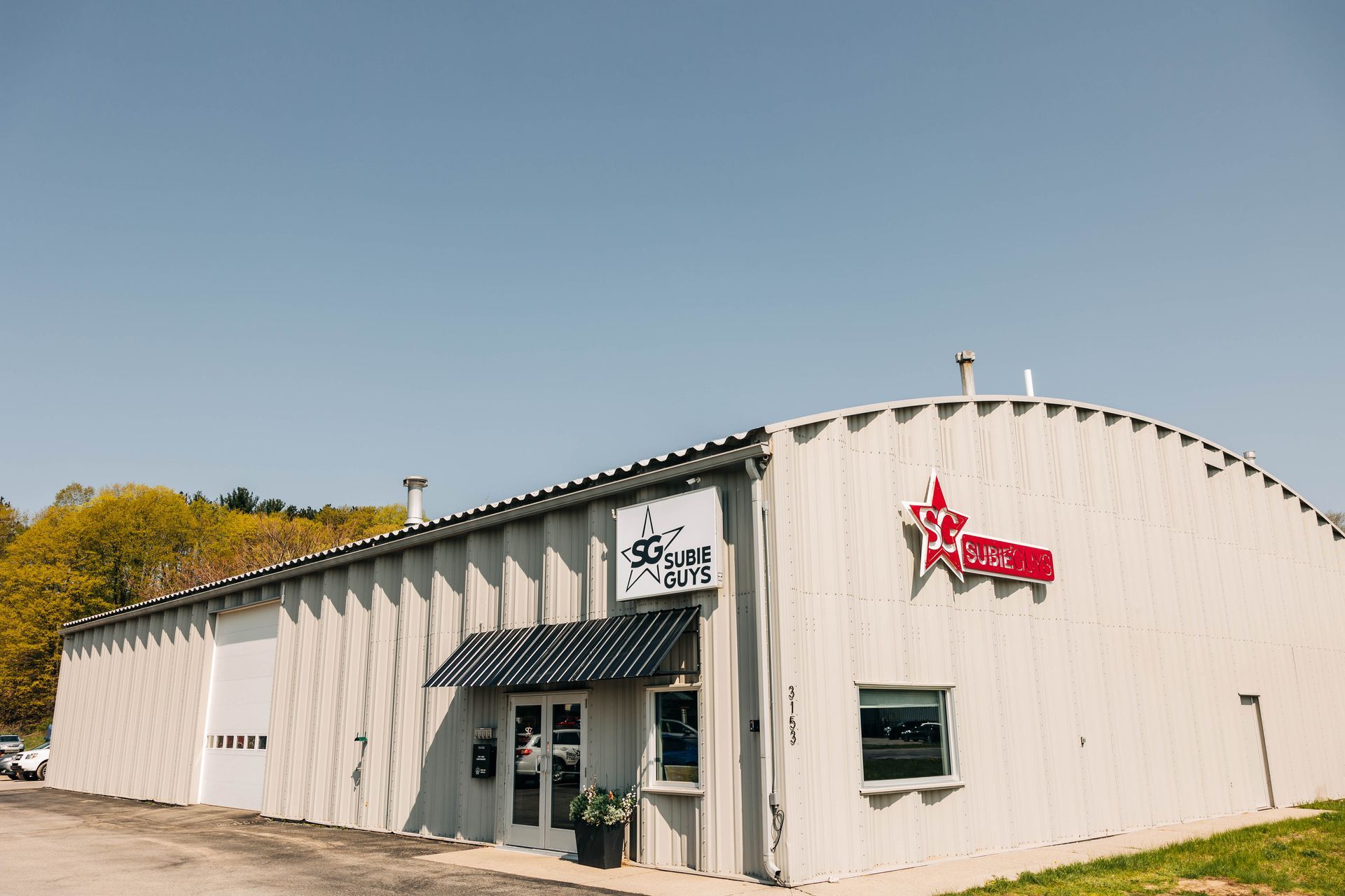 Exterior of a business with a white corrugated metal facade and red signage. | Empower Automotive