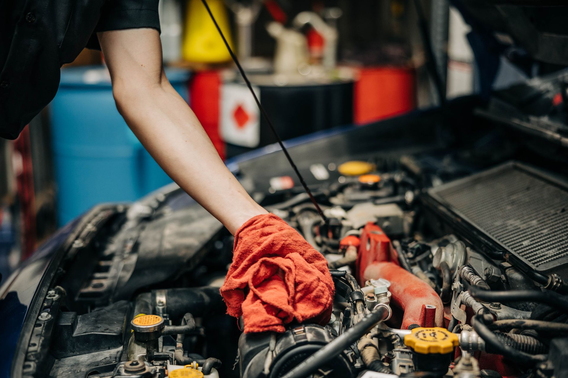 A person with a red rag, working on a car engine in a garage. | Empower Automotive