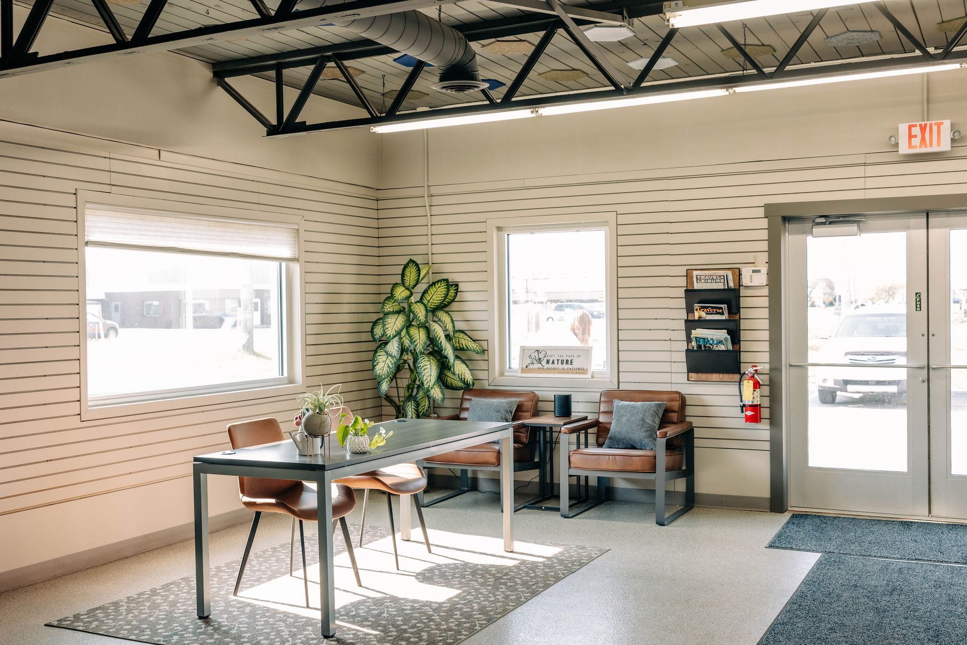 Reception area with table, chairs, and potted plant against horizontally striped walls. | Empower Automotive